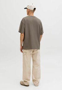 Prevelika olivno zelena majica s kratkimi rokavi, združena z bež cargo hlačami z bočnimi žepi in sproščenim krojem.