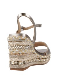 Metallisch goldene Wedge-Sandalette mit einem geflochtenen Jute- und Stoffriemen, verziert mit Perlen und Strass entlang der Sohle.