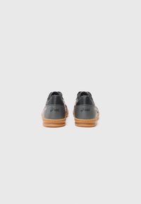 Zwarte sportieve schoenen met een roze logo, gestructureerde bovenkant en rubberen zolen van rubber. Heeft contrasterende stiksels en een vlakke hakontwerp.