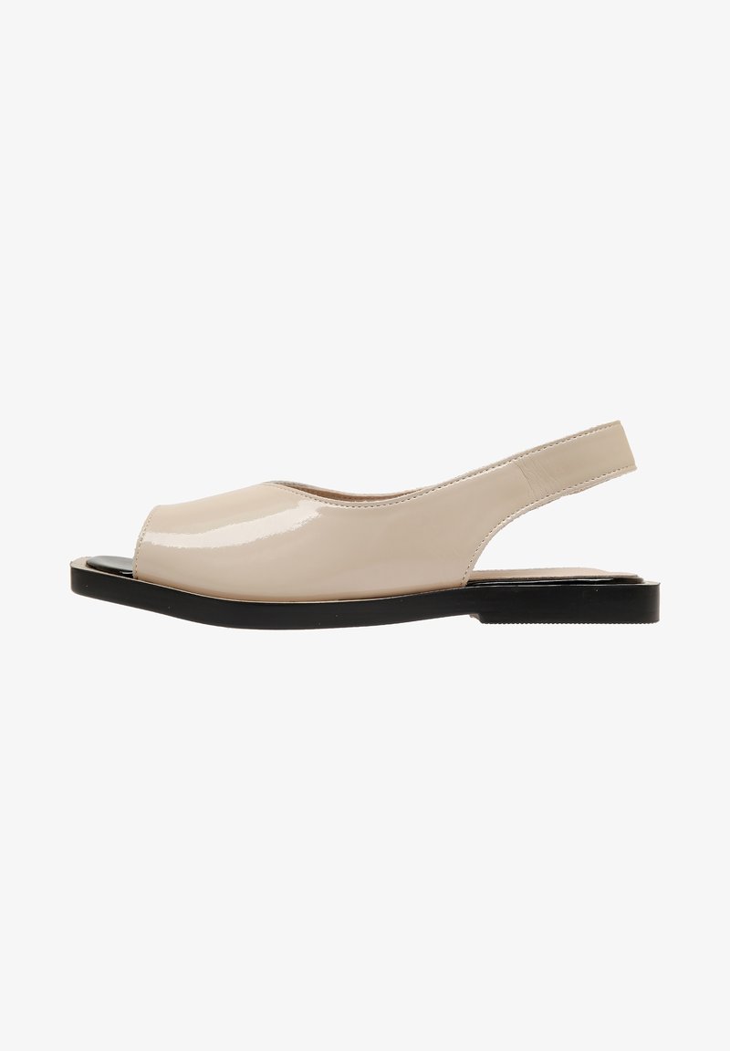 Chaussure plate beige en cuir verni à bout ouvert avec semelle noire, vue de côté sur fond blanc.
