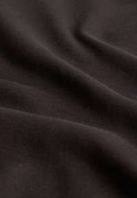 Mustast kangast, millel on sile tekstuur, veidi peegeldav pind ja õrn venivus, mis langeb õrnadesse voldikutesse.