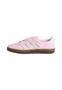 Pink suede sneaker with three white stripes, textured brown rubber sole, and "GAZELLE" branding. Low profile design with lace closure.