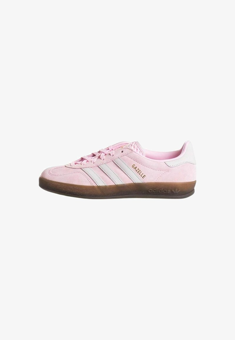 Pink suede sneaker with three white stripes, textured brown rubber sole, and "GAZELLE" branding. Low profile design with lace closure.