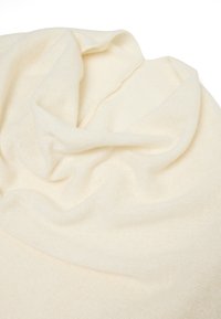 Lichtbeige gebreide sjaal van een zachte, textuurrijke stof, met losse plooien en een over het algemeen gladde uitstraling.