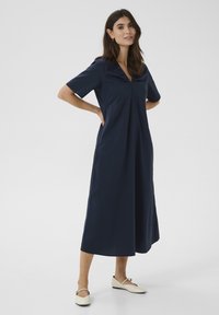 Temno modra kratek rokav obleka z V-izrezom in detajlom volanov, lahkotno A-linijo, mehkimi materiali in dolžino do sredine tele.