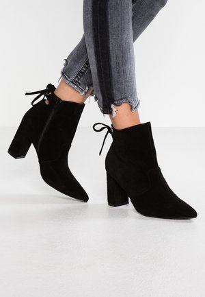 Bottines en suède noir avec un bout pointu, une fermeture éclair sur le côté et un accent en dentelle à l'arrière. Dotées d'un talon épais et d'un matériau texturé.