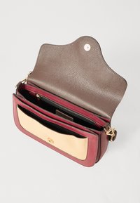 Piccola borsa a tracolla in pelle di colore bordeaux, beige e marrone con chiusura dorata, più scomparti e una patta aperta che mostra una tasca interna con zip.