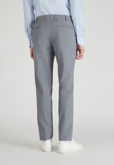 Pantalones grises con un patrón, hechos de una tela ligera, con un corte recto, bolsillos traseros, y combinados con zapatillas blancas.