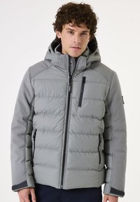 Chaqueta de abrigo gris con capucha, que presenta un tejido acolchado, bolsillos con cremallera y un detalle de cremallera negra. Material suave y aislante.