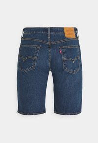 Tmavě modré džínové šortky s rovnou siluetou, pěti kapsami a koženou nášivkou na zadním pasu s žlutými prošívacími detaily.