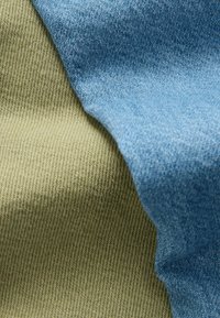 Katoenen stof in blauw en olijfgroen, met een gestructureerde weving. De twee kleuren overlappen elkaar op veelkleurige randen, wat zorgt voor duidelijke tinten en patronen.