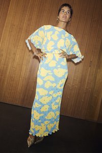 Maxi šaty v modré barvě se žlutým abstraktním vzorem, volným střihem, vlnitým lemem a krátkými rukávy, doplněné o kovové vysoké podpatky.