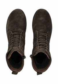 Un paio di stivaletti in suede marroni scuri con lacci e cerniere laterali, visti dall'alto su uno sfondo bianco.