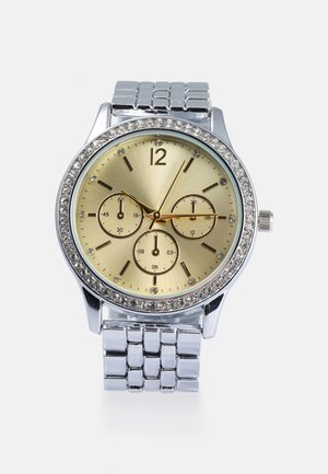 Relógio de metal prateado com um mostrador em tom de ouro, três submostradores e uma luneta acentuada com cristais. Apresenta um design de bracelete ligado.