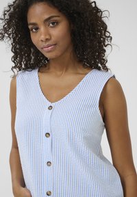 Robe sans manches à rayures bleues et blanches avec un décolleté en V, ornée de grands boutons marron sur le devant et d'une coupe décontractée. Tissu texturé.