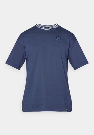 T-shirt en coton bleu marine à manches courtes, doté d'un col rond avec une bande de texte "Just Do It" et d'un logo brodé sur la poitrine.