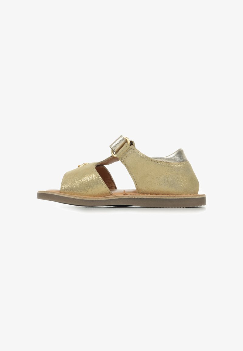 Sandalia de cuero metálico dorado con punta abierta, correa ajustable y suela plana. Presenta un brillo sutil y un diseño simple y minimalista.