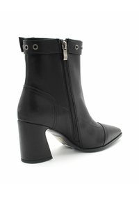 Czarne skórzane botki za kostkę z ostrym noskiem, bocznym zamkiem błyskawicznym i masywnym obcasem. Posiadają srebrne detale oraz dekoracyjny pasek z oczkami.