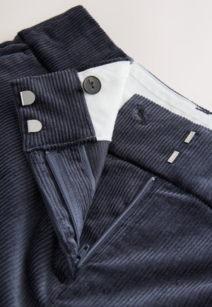 Námornícke kordové nohavice s predným zipsom, zapínaním na gombík a kovaniami striebornej farby. Tkanina má textúrovaný rebrovaný vzor.