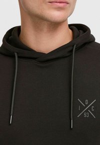Dunkelgrüner Kapuzenpullover aus strukturiertem Material. Verfügt über einen runden Halsausschnitt, Kordelzüge und ein Logodesign mit "I D C 93."