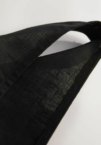 Tissu noir à texture lisse, doté d'un design à double couche et de bords contrastants. Le matériau semble léger et flexible.