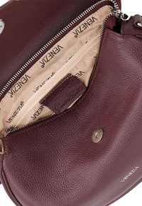 Burgunderfarbene Leder-Umhängetasche mit strukturierter Oberfläche, ausgestattet mit einem Reißverschluss und einer Innentasche mit Reißverschluss, gebrandeter Innenausstattung und Logo-Akzent.