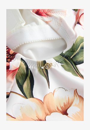 Stoff mit Blumenmuster, der große rosa und gelbe Blumen auf weißem Hintergrund zeigt. Beinhaltet einen goldenen kreisförmigen Akzent und hat eine glatte Textur.