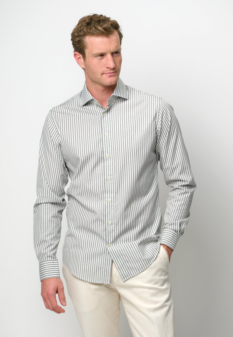 Gestreifte Button-Up-Hemd aus grauem und weißem Stoff mit langen Ärmeln, ausgestattet mit einem Kentkragen und Knopfleiste, kombiniert mit hellen Hosen.