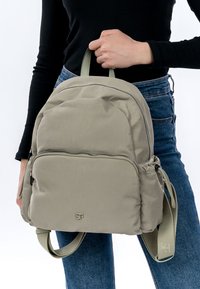 Vaaleanharmaa nailonreppu pyöreällä muotilla, kaksinkertaisilla yläkahvoilla, etutaskulla vetoketjulla ja säädettävillä olkahihnoilla. Varustettu kohokuvioidulla logolla.