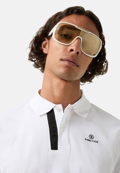 White polo shirt with a black vertical stripe featuring "FIRE + ICE" branding, worn with oversized sunglasses with yellow lenses.