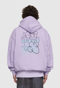Hoodie oversize viola con tasca frontale. Il retro presenta un disegno a linee nere con le parole "Lost Youth" in blu e glitter. Texture morbida.