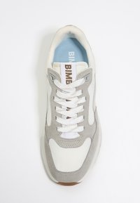 Sneaker z białą skórzaną cholewką, szarymi zamszowymi akcentami i jasnoniebieską wkładką. Posiada okrągłe sznurowadła i metkę z logo na języku.