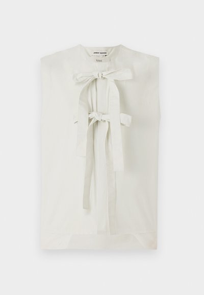 Sleeveless white blouse made of smooth fabric. Features a central opening secured with two bow ties, and a straight, relaxed fit.