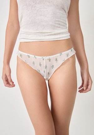 Perizoma bianco trasparente con ricami floreali in piccoli motivi viola e verdi, rifinito con un delicato pizzo e un piccolo fiocco sul davanti.