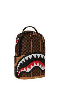Mochila de cuadros marrones con un diseño de boca de tiburón en tonos rojo y blanco. Incluye un asa en la parte superior y cierre con cremallera.