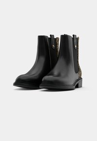 Černé kožené Chelsea boty s leopardími bočními panely, plochou podrážkou a zlatými akcenty. Hladká textura, design do výšky kotníku.