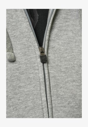 Pilkos spalvos užtrauktukas su glotnaus audinio tekstūra, metaliniu užtrauktuku ir maža logotipo etikete ant užtrauktuko. Matomi gobtuvas ir priekinės kišenės detalės.