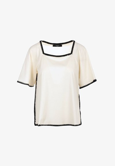 Top a maniche corte di colore crema con scollo quadrato, dotato di rifiniture nere a forma di scallop lungo i bordi e i lati. Tessuto morbido.