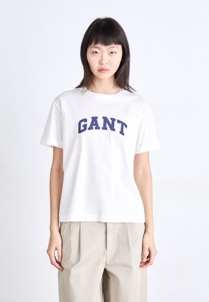 T-shirt bianco in cotone con logo "GANT" curvato in navy sul petto. Maniche corte e vestibilità rilassata con orlo dritto.