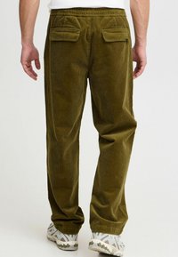 Olive green corduroy pants with a relaxed fit, featuring an elastic waistband and two back pockets. Textured fabric adds visibility to ribbing.