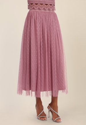Mauve midi skirt with sheer polka dot overlay paired with silver high-heeled sandals on model against plain background.