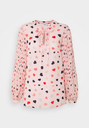 Blouse rose clair à manches longues avec motifs de cœurs multicolores, manches plissées et détail œillet à l'avant avec lien noué au col.