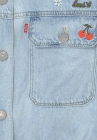 Světle modrá džínová bunda s přední kapsou se stříbrnými knoflíky, vyšívaným designem třešní a červenou nášivkou Levi's na kapse.