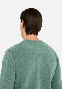 Maglione lavorato a maglia in verde mottled, con scollo rotondo e superficie testurizzata. Presenta una vestibilità rilassata e delicati dettagli a coste ai polsini.
