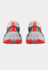 Ζευγάρι αθλητικών παπουτσιών με γκρι και μαύρο διχτυωτό επάνω μέρος, χοντρές λευκές ενδιάμεσες σόλες και φωτεινές κόκκινες γλωττίδες στη φτέρνα και εξωτερικές σόλες, από την πίσω όψη.
