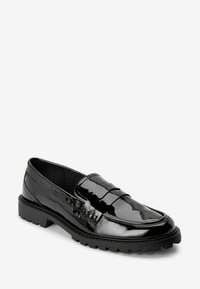 Schwarzer glänzender Leder-Slipper mit geriffelter Sohle und Mokassinstil-Naht auf weißem Hintergrund.