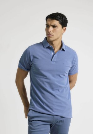 Polo azul claro hecho de algodón, con un collar clásico y una tapeta de dos botones. Mangas cortas con un diseño ajustado.