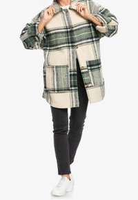 Abrigo de mezcla de lana a cuadros con tonos verdes y beige, diseño oversize, cierre de botones, grandes bolsillos y mangas con puños doblados.