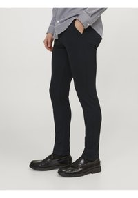 Námořnické slim-fit kalhoty vyrobené z texturované tkaniny, s bočními kapsami a hladkým povrchem, kombinované s černými mokasíny pro kompletní vzhled.