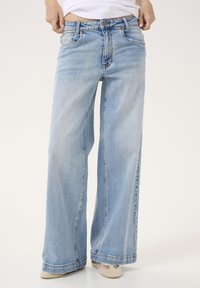 Jeans a gamba larga azzurro chiaro con un lavaggio sbiadito, vita aderente, chiusura con bottone in metallo e cinque tasche. Il tessuto è denim con una leggera texture.